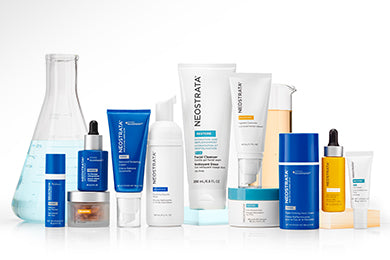 An array of bottles of Neostrata Skincare and beakers, on a white background.
