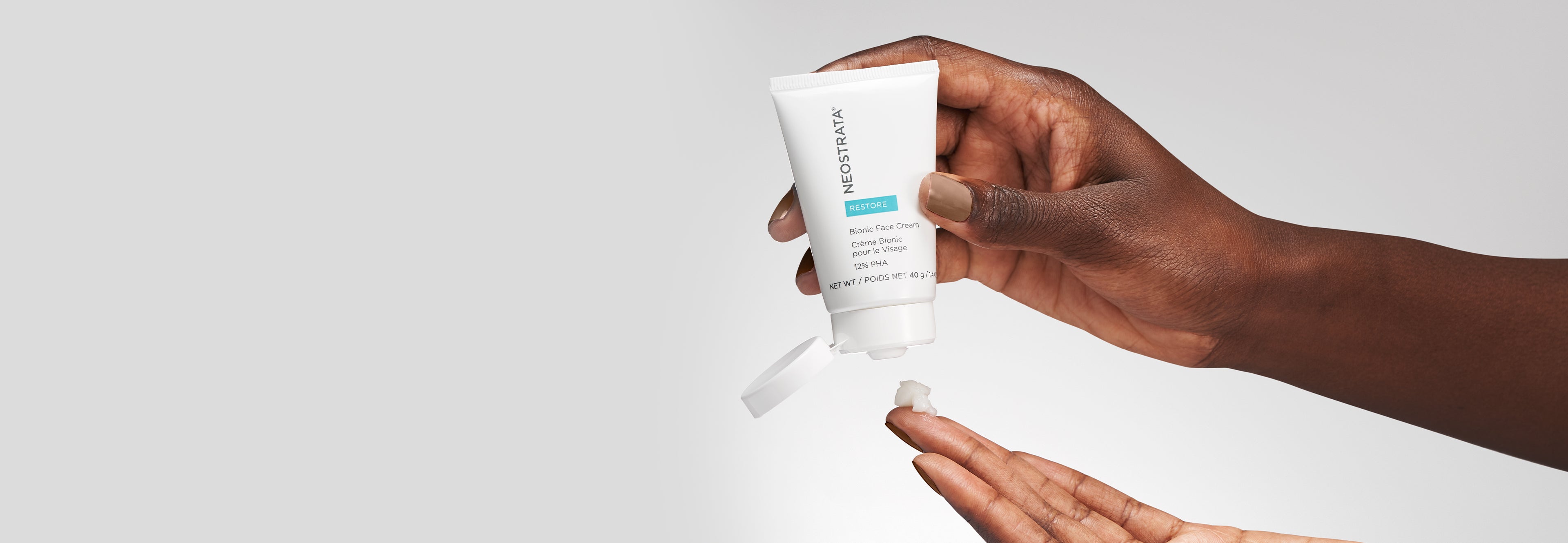 Pair of hands holding a bottle of Neostrata Bionic Face Cream against a white background.