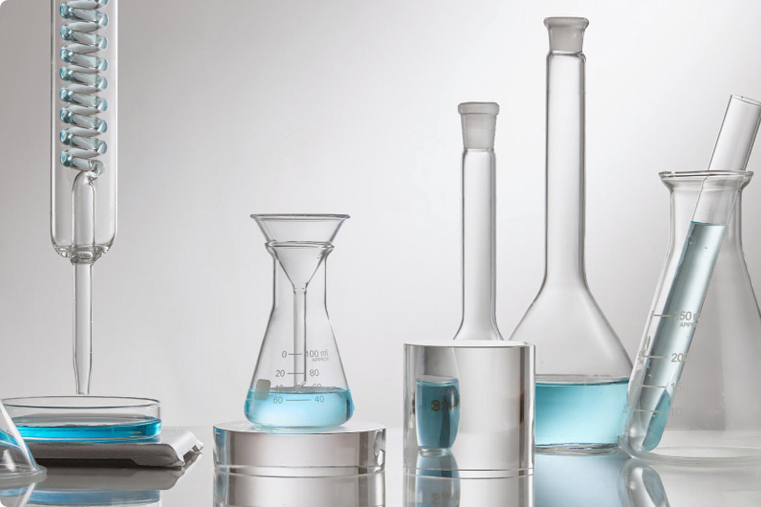 An array of beakers filled with a light blue liquid on a gray background.