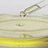 A video of a dropper featuring a golden liquid being dropped into a petri dish.